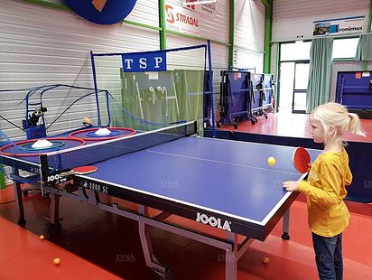La jeune Tabéa, 6 ans, s’essaie au tennis de table avec un robot lanceur de balles.